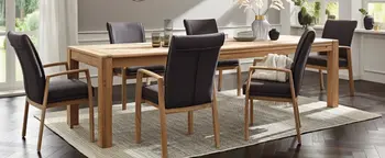 Esszimmer mit rechteckigem Holztisch und sechs dunklen Polsterstühlen auf hellem Teppich vor großen Fenstern.
